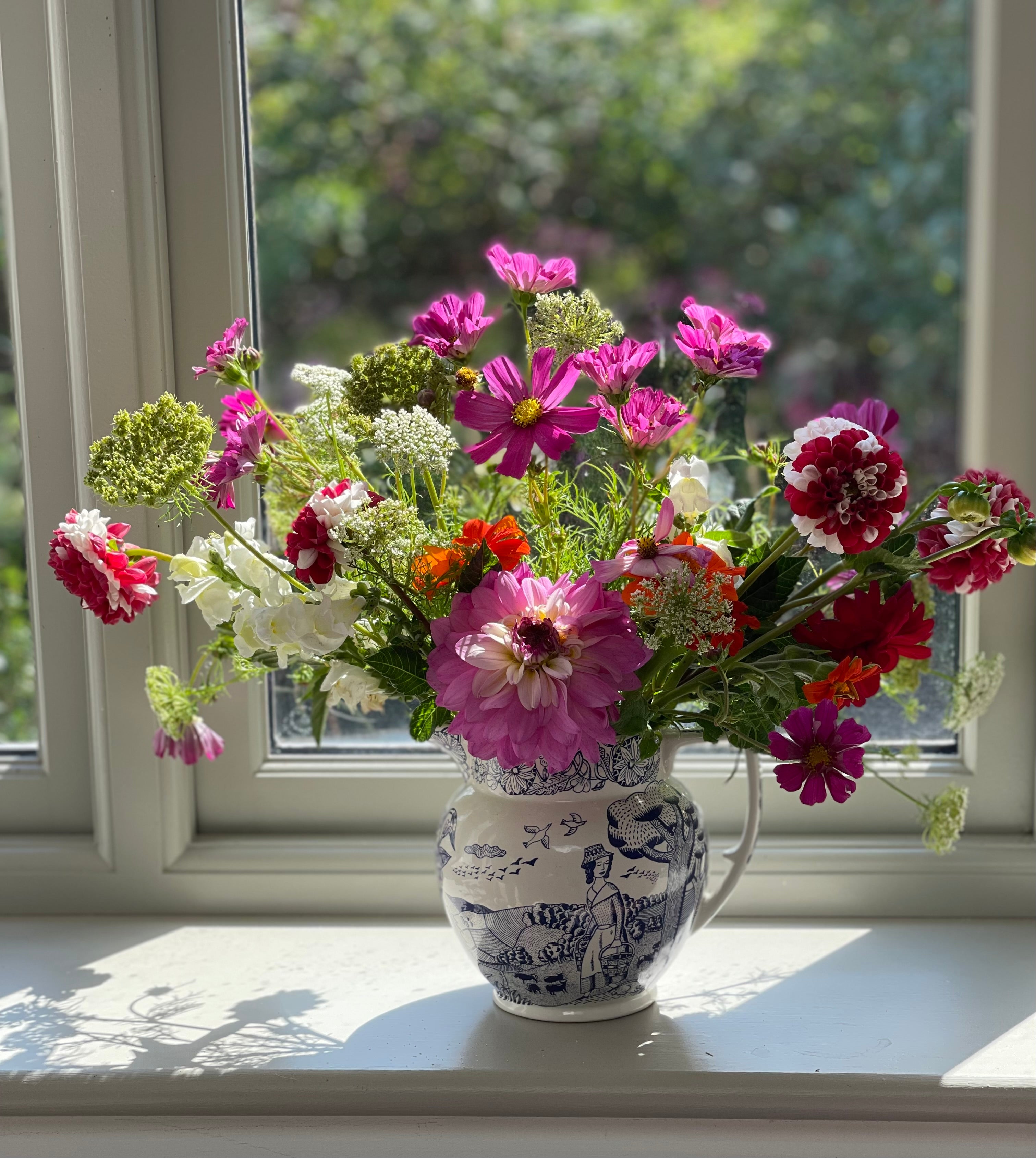 Photograph of cosmos, peonies and dahlias in vintage blue and white jug.